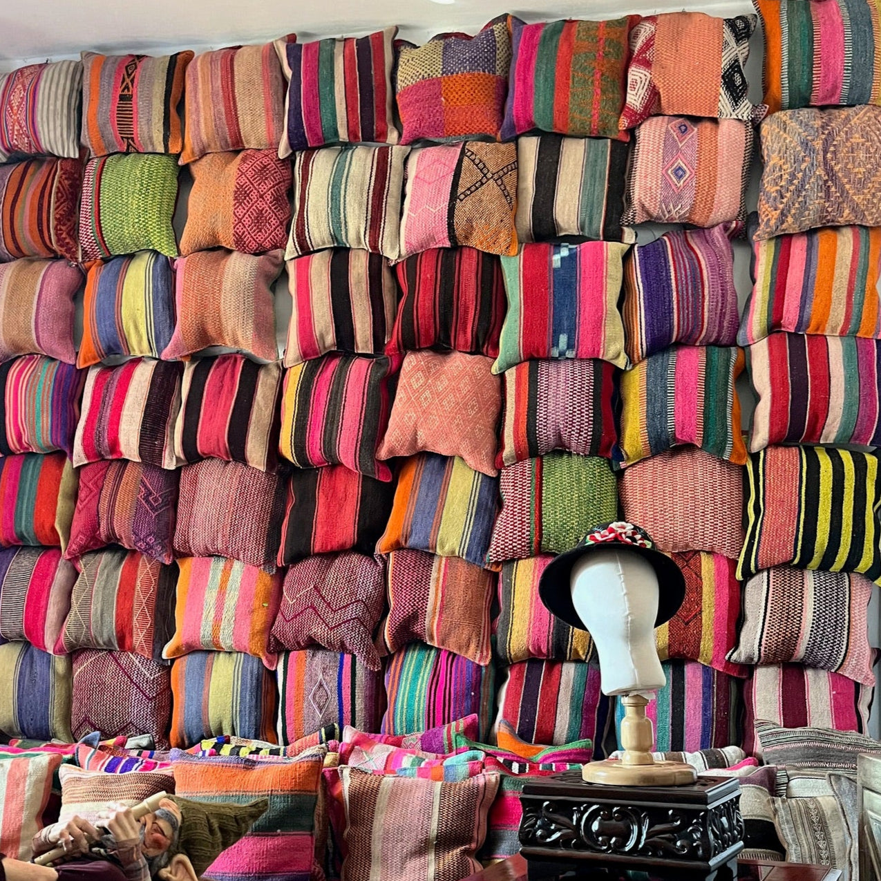 Grote wand vol kussens met hoedje op voorgrond